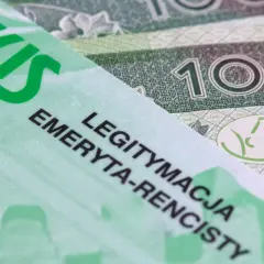 Zielona legitymacja ZUS "EMERYTA-RENCISTY" na tle banknotów 100 zł. Dokumenty te są kluczowe, gdy zastanawiasz się, co potrzebne do renty chorobowej.