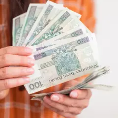 Ręce trzymające polskie stuzłotówki. Zastanawiasz się, ile wynosi emerytura pomostowa?