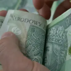 Dłonie przeglądają stos banknotów 100 zł. Czy to wystarczy na rehabilitację i ile trwa renta rehabilitacyjna?