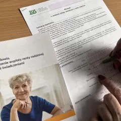 Uśmiechnięta starsza pani na zdjęciu obok formularza ZUS. Dokument dotyczy ustalenia zbiegu świadczeń z rentą rodzinna, czyli co to jest renta rodzinna.