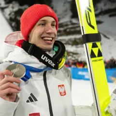 Uśmiechnięty skoczek narciarski w czerwonej czapce trzyma srebrny medal. Czy za dwa medale olimpijskie są dwie emerytury?