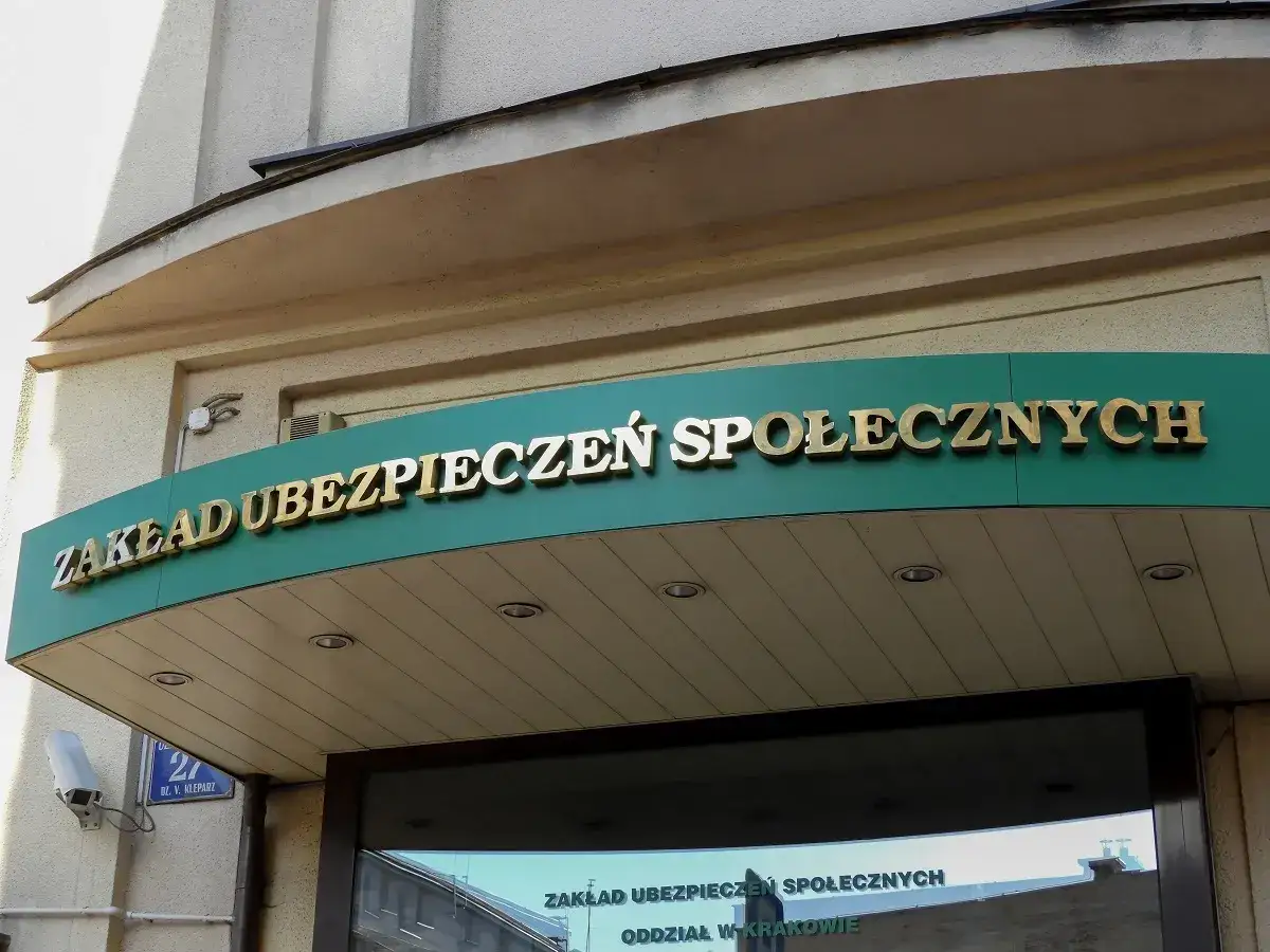ZUS. Czy praktyki liczą się do emerytury? Złote litery na zielonym tle nad wejściem do placówki.
