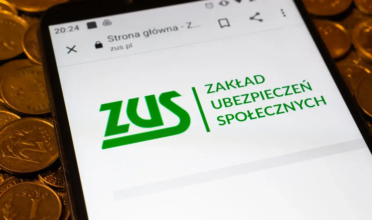Poradnik: jak chorobowe wpływa na wysokość emerytury. Na ekranie telefonu logo ZUS i monety.