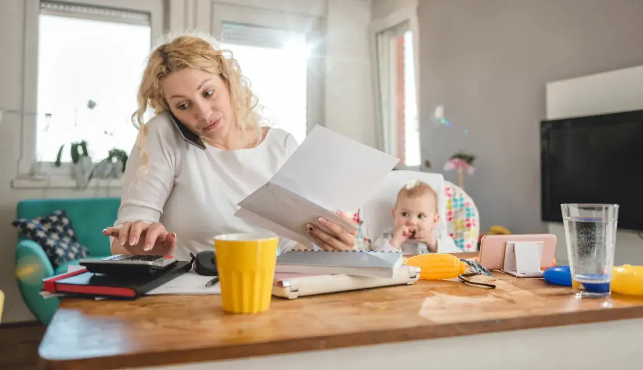 Zabiegana mama z dzieckiem przy biurku, martwiąca się, czy komornik może zająć rentę rodzinną po mężu.